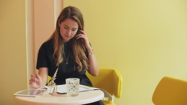 Affärskvinna som sitter vid ett bord på ett café, dricka kaffe och arbetar på en surfplatta — Stockvideo