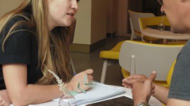 Bir iş kadını ve bir adam kendi tablet ile onların kopma sarı duvarlı bir kafede oturup bir projeyi tartışmak