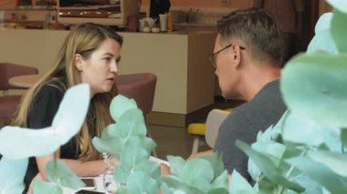 Bir iş kadını ve bir adam kendi tablet ile onların kopma sarı duvarlı bir kafede oturup bir projeyi tartışmak