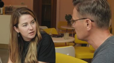 Bir iş kadını ve bir adam kendi tablet ile onların kopma sarı duvarlı bir kafede oturup bir projeyi tartışmak