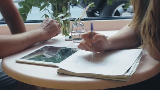 Een zakenvrouw en een man bij hun breuk met hun tablet zitten in een cafe met gele muren en bespreken van een project — Stockvideo