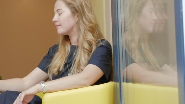 Mujer de negocios sentada en una mesa en un café bebiendo café y utiliza en un teléfono inteligente — Vídeos de Stock