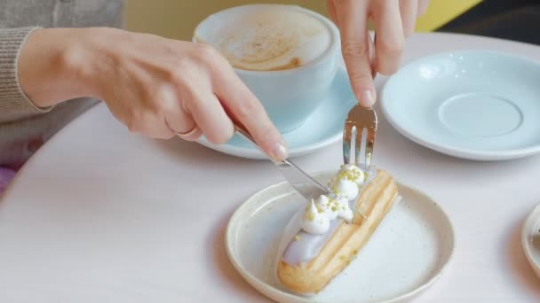 Dos mujeres sentadas en un restaurante cafetería comiendo pasteles eclair bebiendo café y riendo — Vídeo de stock