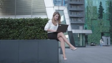 Şehir park iş merkezi içinde laptop üzerinde çalışan genç iş kadını