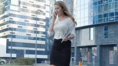 Genç iş kadını konuşmak smartphone şehir park iş merkezinde kullanıyor