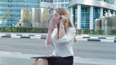 Genç iş kadını konuşmak smartphone şehir park iş merkezinde kullanıyor