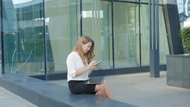 Young business woman talking is using smartphone in city park business center — Stock Video