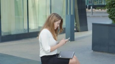 Genç iş kadını konuşmak smartphone şehir park iş merkezinde kullanıyor