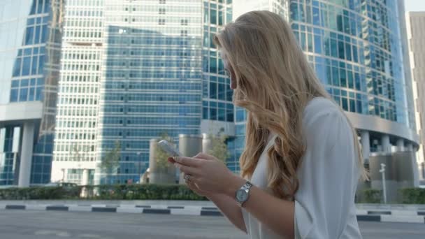 Joven mujer de negocios hablando está utilizando el teléfono inteligente en el centro de negocios del parque de la ciudad — Vídeos de Stock