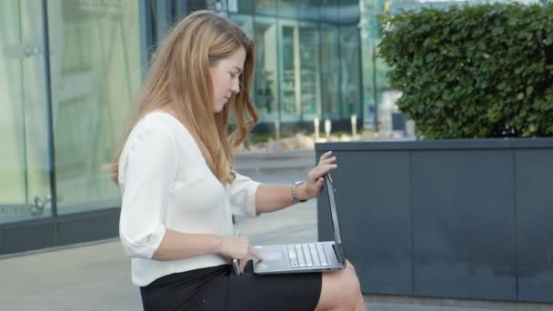 Young businesswoman working on laptop in city park business center — Stock Video