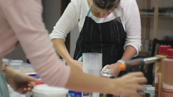 Женщины в художественной студии смешивают краски и рисуют на холсте в технике жидкого искусства — стоковое видео