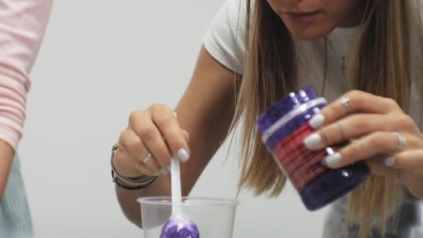 Women in an art studio mix paints and draw on canvas in fluid art technique — Stock Video