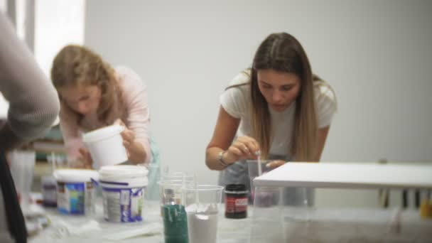 Frauen im Kunstatelier mischen Farben und zeichnen auf Leinwand in flüssiger Kunsttechnik — Stockvideo