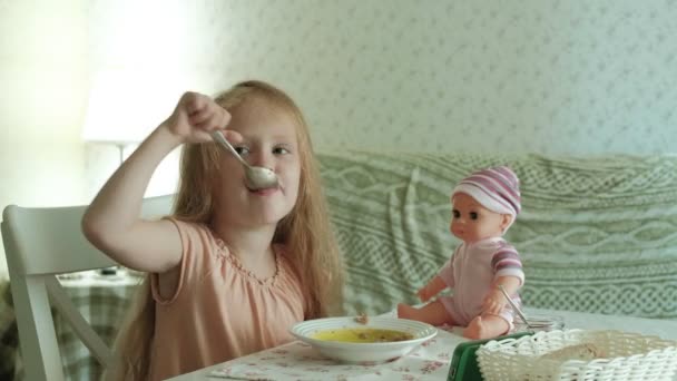 Heureuse belle fille manger du porridge pour le petit déjeuner et s'amuser dans la cuisine blanche à la maison — Video