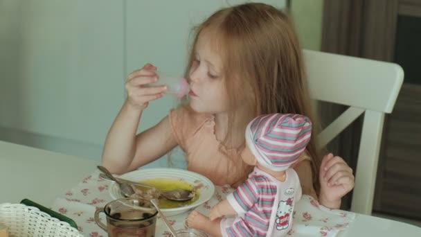 Menina bonita feliz comer mingau de cereal para o café da manhã e se divertir na cozinha branca em casa — Vídeo de Stock