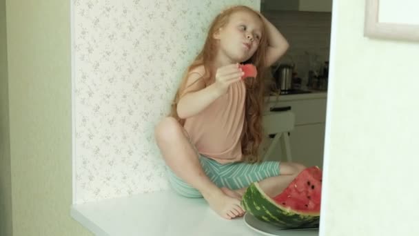 Little girl eating a watermelon in the summer in the kitchen at home — Stock Video