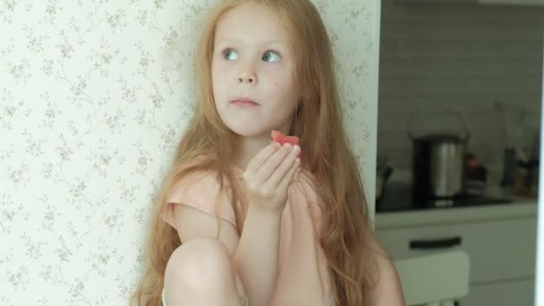 Niña comiendo una sandía en el verano en la cocina en casa — Vídeos de Stock