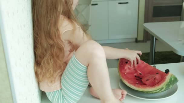 Meisje een watermeloen in de zomer eten in de keuken thuis — Stockvideo