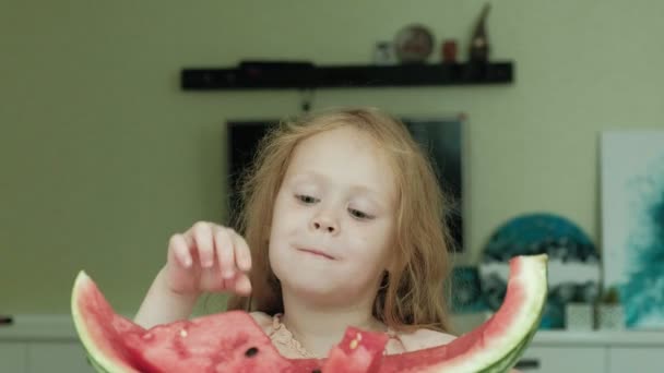 Little girl eating a watermelon in the summer in the kitchen at home — Stock Video