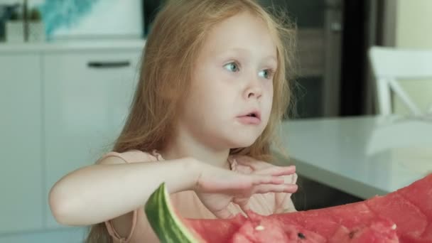 Meisje een watermeloen in de zomer eten in de keuken thuis — Stockvideo