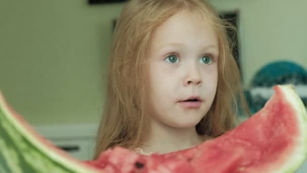 Meisje een watermeloen in de zomer eten in de keuken thuis — Stockvideo