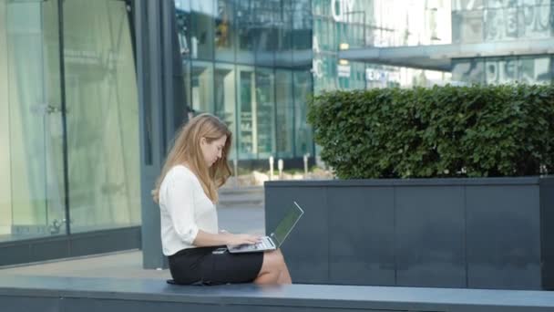 Joven mujer de negocios que trabaja en el ordenador portátil en el centro de negocios del parque de la ciudad — Vídeos de Stock