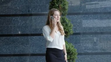 Genç iş kadını konuşmak smartphone şehir park iş merkezinde kullanıyor