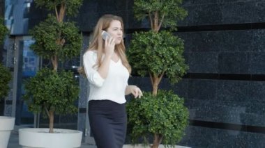 Genç iş kadını konuşmak smartphone şehir park iş merkezinde kullanıyor