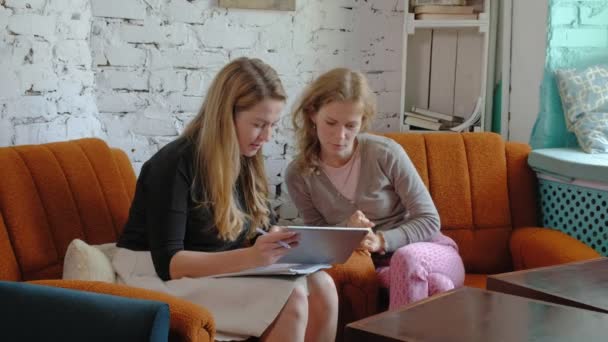 Two business women using a touchpad in the office are busy discussing matters — Stock Video