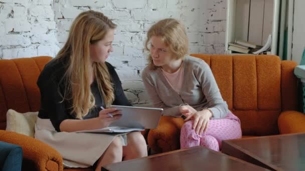 Two business women using a touchpad in the office are busy discussing matters — Stock Video