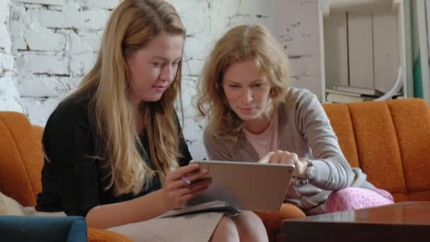 Two business women using a touchpad in the office are busy discussing matters — Stock Video