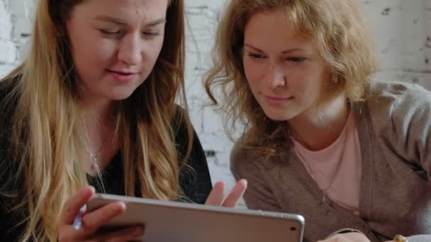 Two business women using a touchpad in the office are busy discussing matters — Stock Video