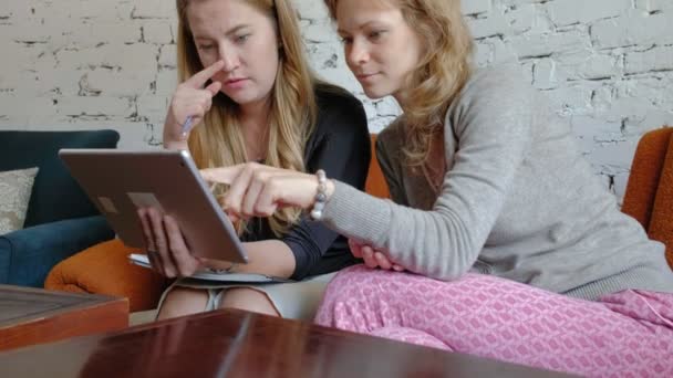 Дві ділові жінки, які використовують тачпад в офісі, зайняті обговоренням питань — стокове відео