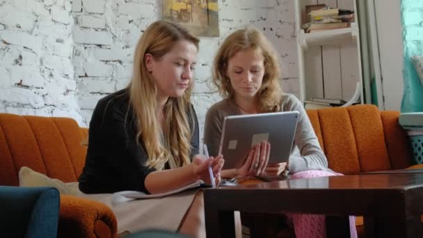 Two business women using a touchpad in the office are busy discussing matters — Stock Video