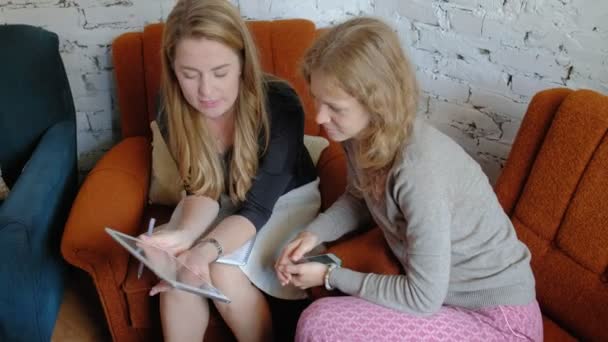 Two business women using a touchpad in the office are busy discussing matters — Stock Video