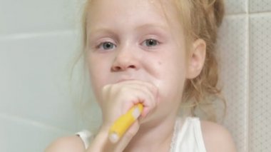 Küçük kız özenle aynaya Dişlerini fırçalıyor.