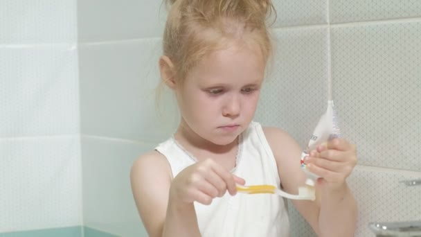 Маленька дівчинка старанно чистить зуби у дзеркалі . — стокове відео