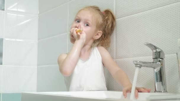 Niña lavándose diligentemente los dientes en el espejo . — Vídeos de Stock