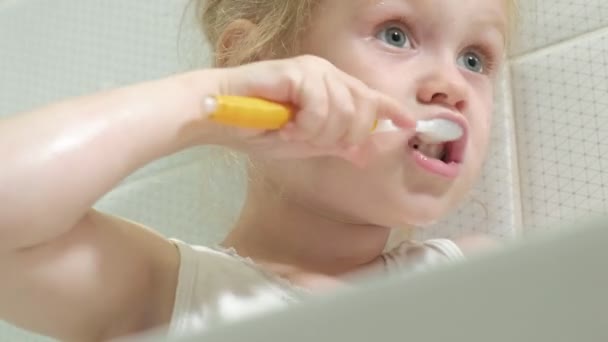 Meisje ijverig zijn tanden te poetsen in de spiegel. — Stockvideo
