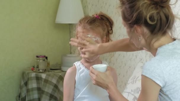 Une femme avec sa fille se moque des masques de concombre à la maison — Video