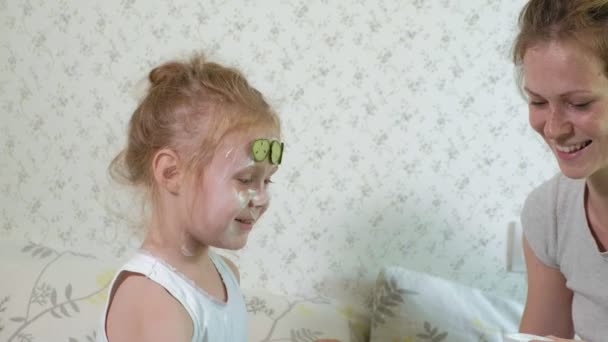 En kvinna med hennes dotter gör narr av gurka masker hemma — Stockvideo