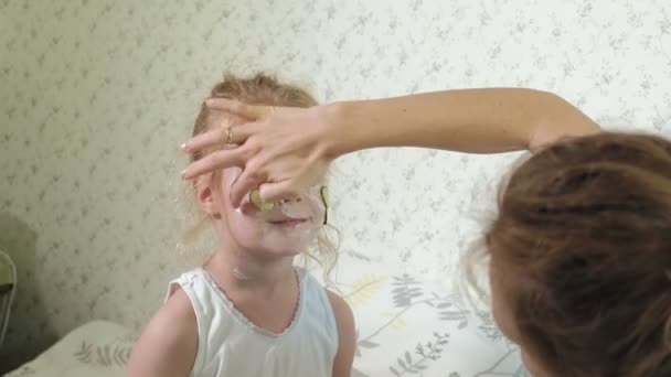 Eine Frau mit ihrer Tochter macht sich zu Hause über Gurkenmasken lustig — Stockvideo