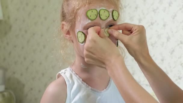 Een vrouw met haar dochter maakt pret van komkommer maskers thuis — Stockvideo