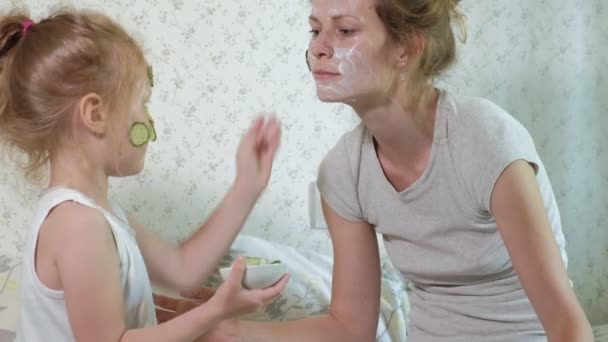 Een vrouw met haar dochter maakt pret van komkommer maskers thuis — Stockvideo