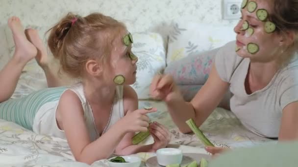 Een vrouw met haar dochter maakt pret van komkommer maskers thuis — Stockvideo