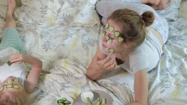 En kvinna med hennes dotter gör narr av gurka masker hemma — Stockvideo