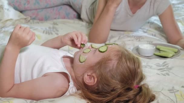 Uma mulher com sua filha faz troça de máscaras de pepino em casa — Vídeo de Stock