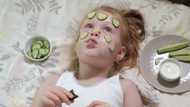 Gyönyörű szép kislány így uborka maszkok otthon, és eszik zöldséget — Stock videók