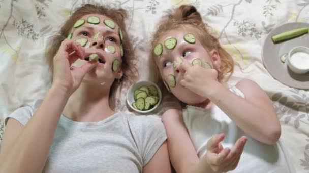 Una mujer con su hija se burla de las máscaras de pepino en casa — Vídeo de stock