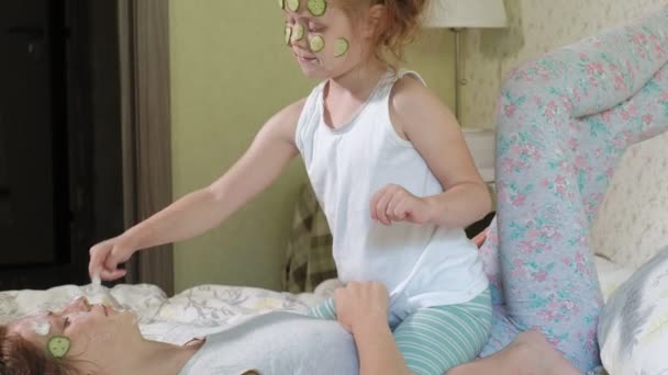 Μια γυναίκα με την κόρη της κάνει τη διασκέδαση του αγγουριού μάσκες στο σπίτι — Αρχείο Βίντεο